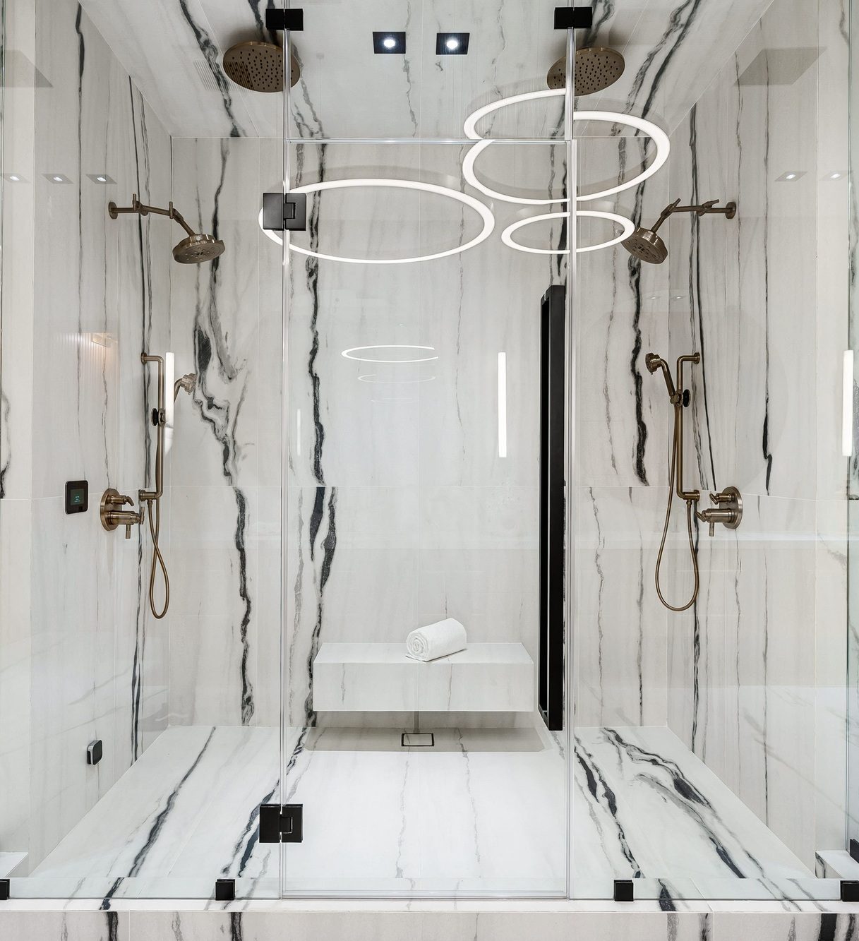 Luxurious modern bathroom with marble walls and glass shower.